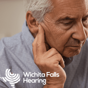 older man holding his ear